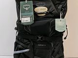 un sac à dos noir muni d'une étiquette, posé par terre