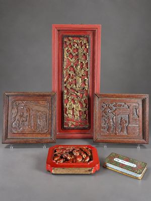 Plusieurs œuvres d'art sont exposées sur une table devant un fond gris.