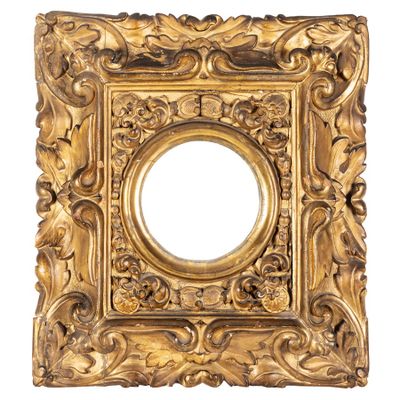 un cadre doré richement décoré, avec un miroir circulaire au centre