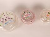 three glass boxes with flowers painted on them sitting on a white surface