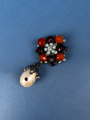 an image of a brooch with beads and stones on a blue surface