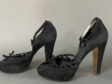 pair of black high heeled shoes with bows on the toes