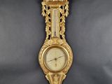 a gold clock hanging on the wall on a black background