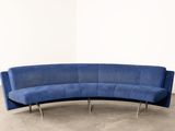 blue curved sofa in a white room with concrete flooring