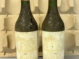 deux bouteilles de vin posées l'une à côté de l'autre devant un mur de briques