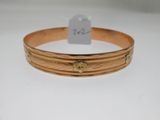 gros plan d'un bracelet en or sur une surface blanche