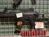 une arme exposée dans une vitrine, avec une étiquette indiquant son prix