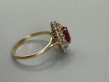 a close up of a gold ring with a ruby and diamond center