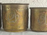 five brass colored vases are lined up on a white table