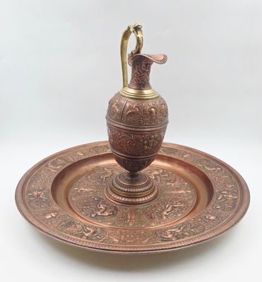 une assiette en métal sur laquelle est posé un vase, sur fond blanc