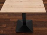 La table est en bois et possède un piètement en métal noir.