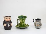 trois figurines en céramique représentant un homme et une femme sont assises l'une à côté de l'autre sur une surface blanche