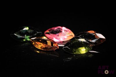 un gros plan sur un ensemble de pierres précieuses de différentes couleurs posées sur une surface noire