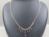 a purple and gold necklace on a mannequin display