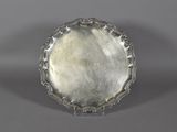 a silver plate on a stand on a gray surface