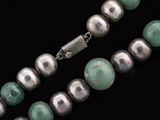 silver and jade bead necklace on a black background
