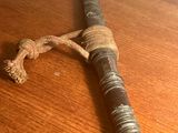 une vieille batte de baseball posée sur une table en bois, attachée par une corde