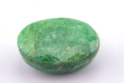 un gros plan d'une pierre verte sur une surface blanche