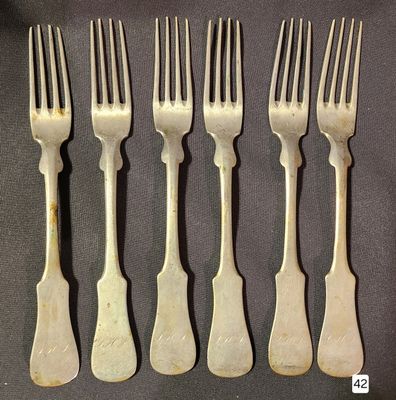 six forks are lined up in a row on a table