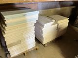 Plusieurs piles de papier sont empilées sur des palettes dans un entrepôt