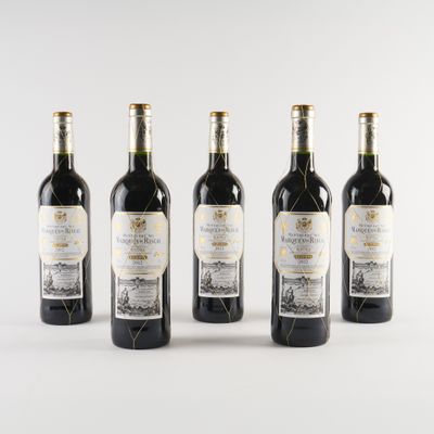 quatre bouteilles de vin sont alignées sur une surface blanche