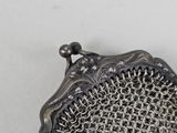 a silver purse with a chain around it on a white surface