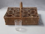 des bouteilles dans un panier en osier, avec un verre posé sur une table