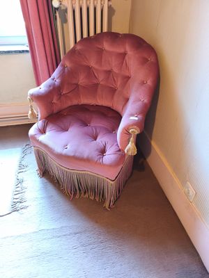 a pink chair that is in a corner of a room