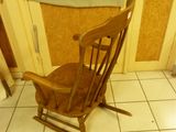 a wooden rocking chair in the corner of a room