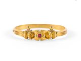 a close up of a gold ring with a red stone in the middle