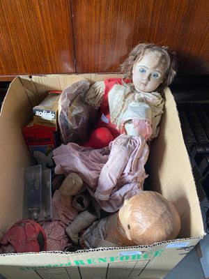 une boîte en carton contenant une poupée, posée par terre