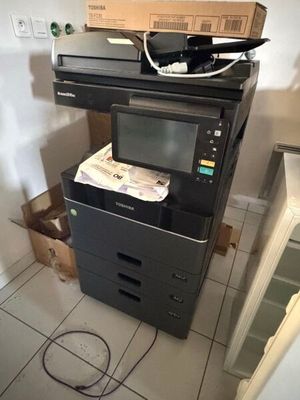 une imprimante noire posée sur une pile de cartons