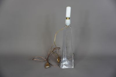 une bouteille en verre sur laquelle est fixée une lampe, reliée à un cordon