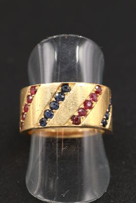 une photo en gros plan d'une bague en or sertie de pierres bleues et rouges
