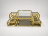 a set of three brass and glass coffee tables on a white background
