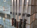 five knives hanging on the wall in the kitchen