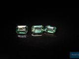 a pair of emeralds on a black surface