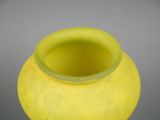 a yellow vase sitting on a table with a gray background