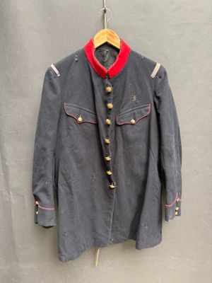 une vieille veste militaire suspendue à un cintre accroché au mur