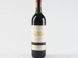 a bottle of red wine sitting on top of a white table