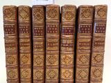six vieux livres sont alignés sur une surface blanche