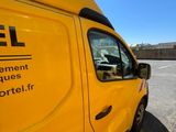 the side of a yellow truck parked in a parking lot next to a building