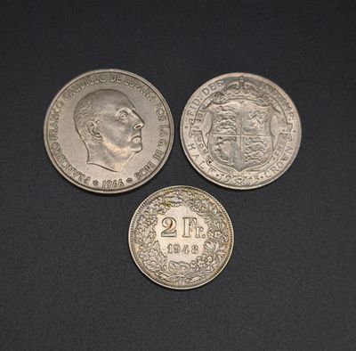 three silver coins sitting on top of each other on a black surface