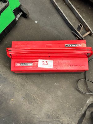 une boîte à outils rouge posée par terre à côté d'autres outils