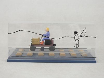 figurine représentant un homme au volant d'un tracteur miniature, avec un panier de biscuits à l'arrière