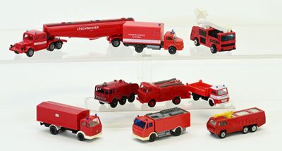 Plusieurs camions de pompiers miniatures sont alignés sur une surface blanche