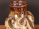 a brown vase with a face on it sitting on a table