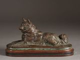 statue of a dog laying on a wooden base on a gray background