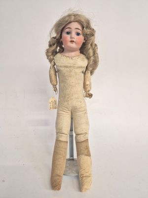 an old doll with blonde hair is standing on a metal stand