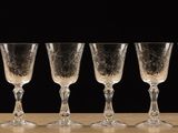 six empty wine glasses lined up on a wooden table